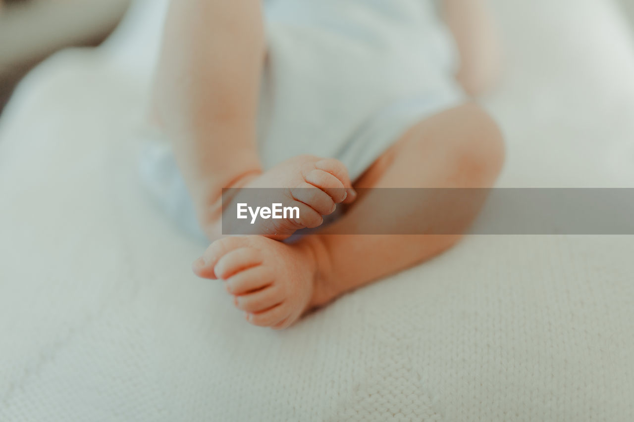 Low section of baby feet on bed at home