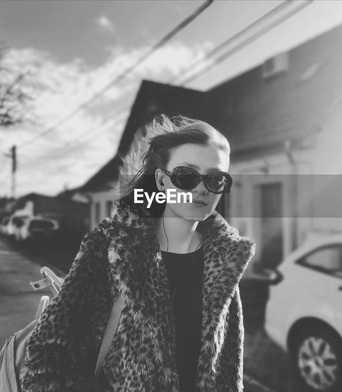 Portrait of a beautiful young woman wearing sunglasses standing by car