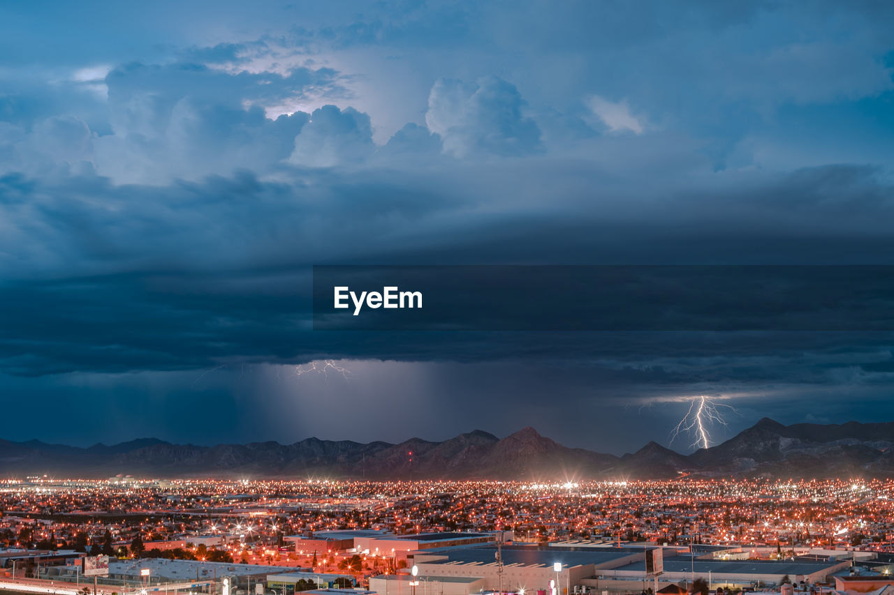 ILLUMINATED BUILDINGS IN CITY AGAINST SKY