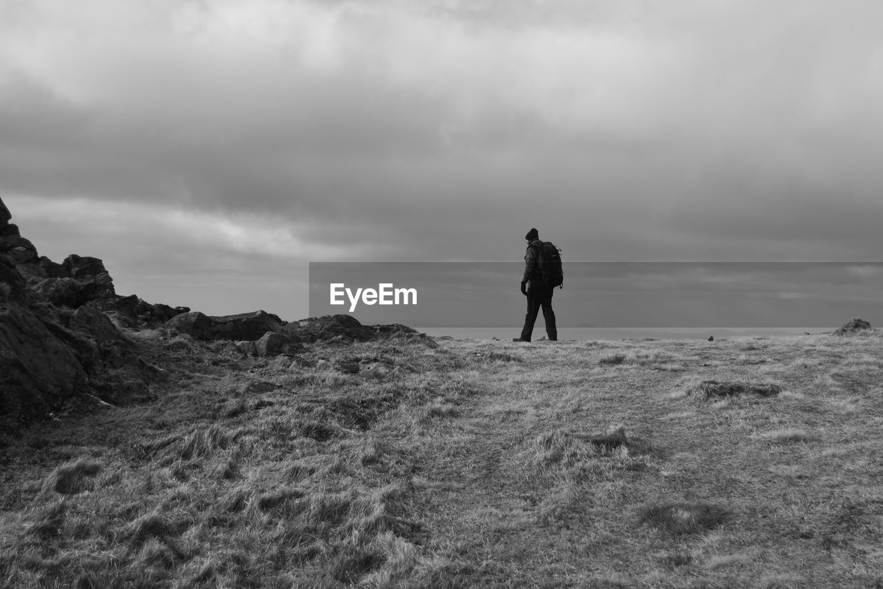 REAR VIEW OF MAN STANDING ON SHORE