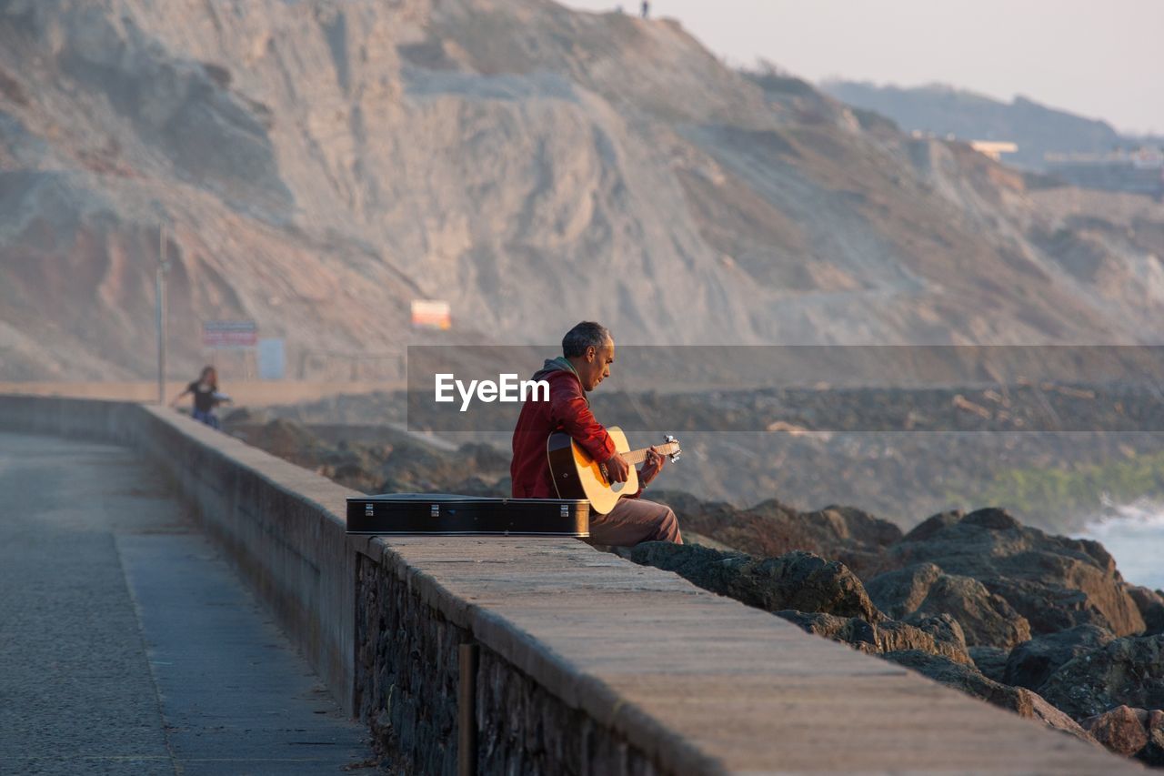 FULL LENGTH OF MAN SITTING ON ROCK