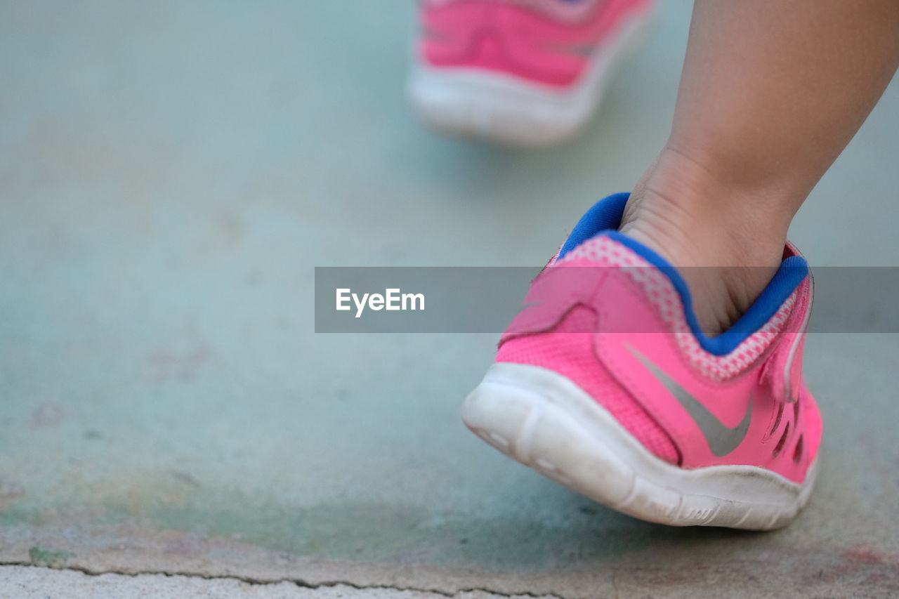 LOW SECTION OF WOMAN WEARING PINK SHOES ON STREET