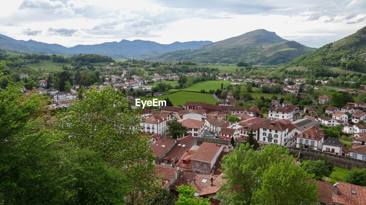 Aerial view of townscape by mountain against sky