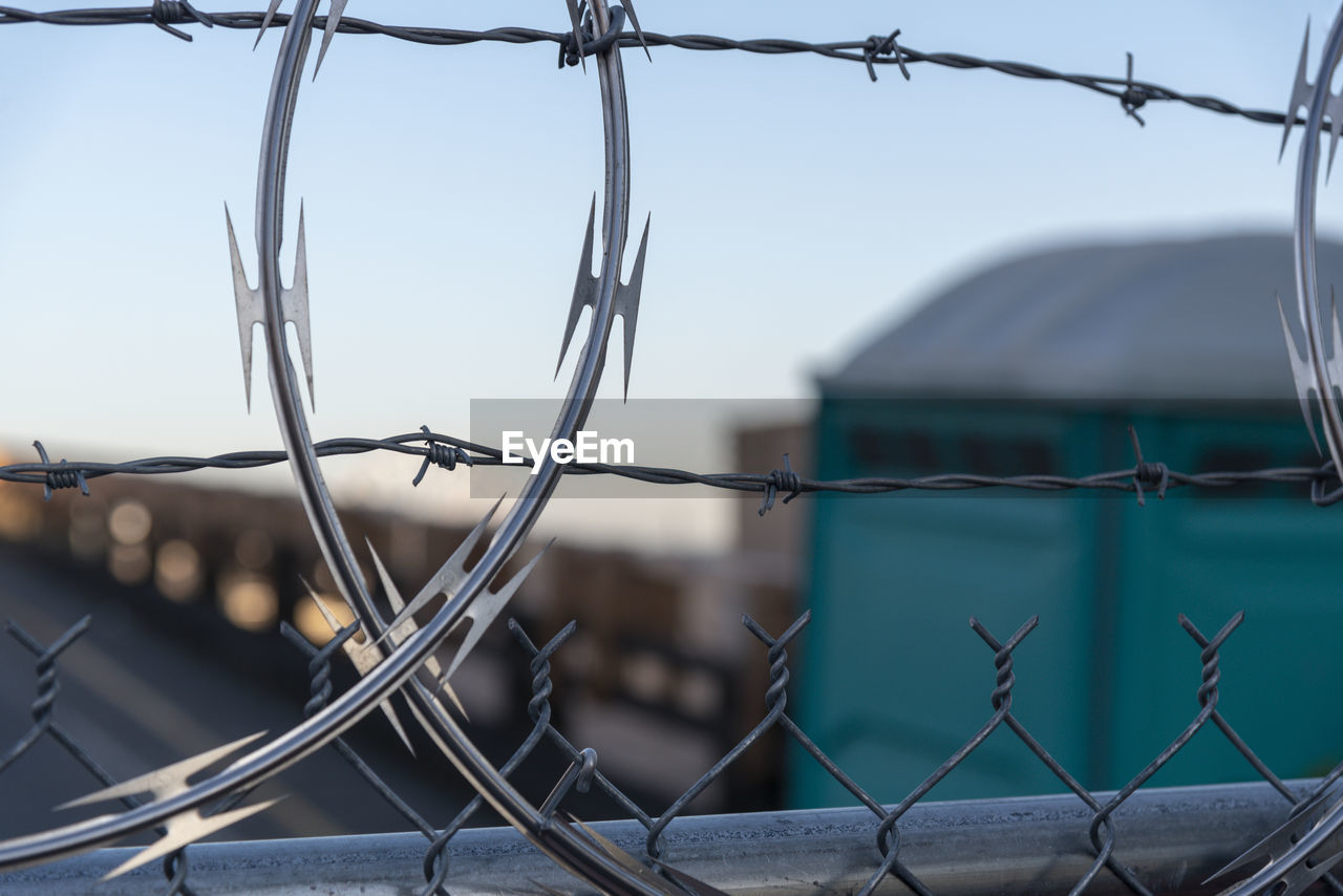 Close-up of barbed wire fence against sky