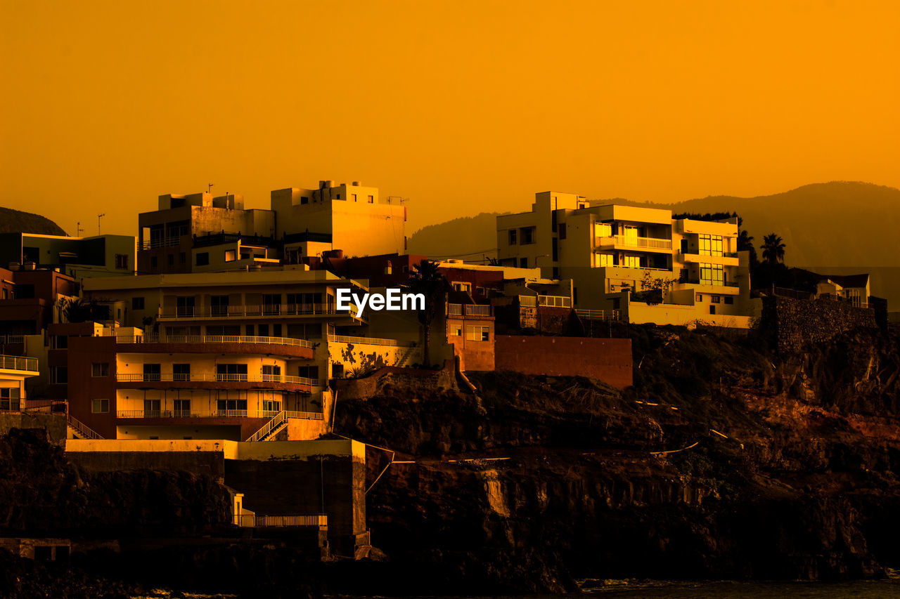 Buildings in city against orange sky