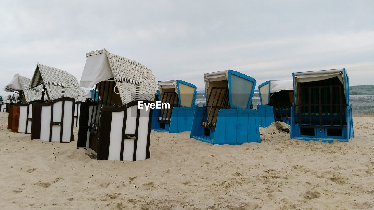 Lounge chairs on beach against sky