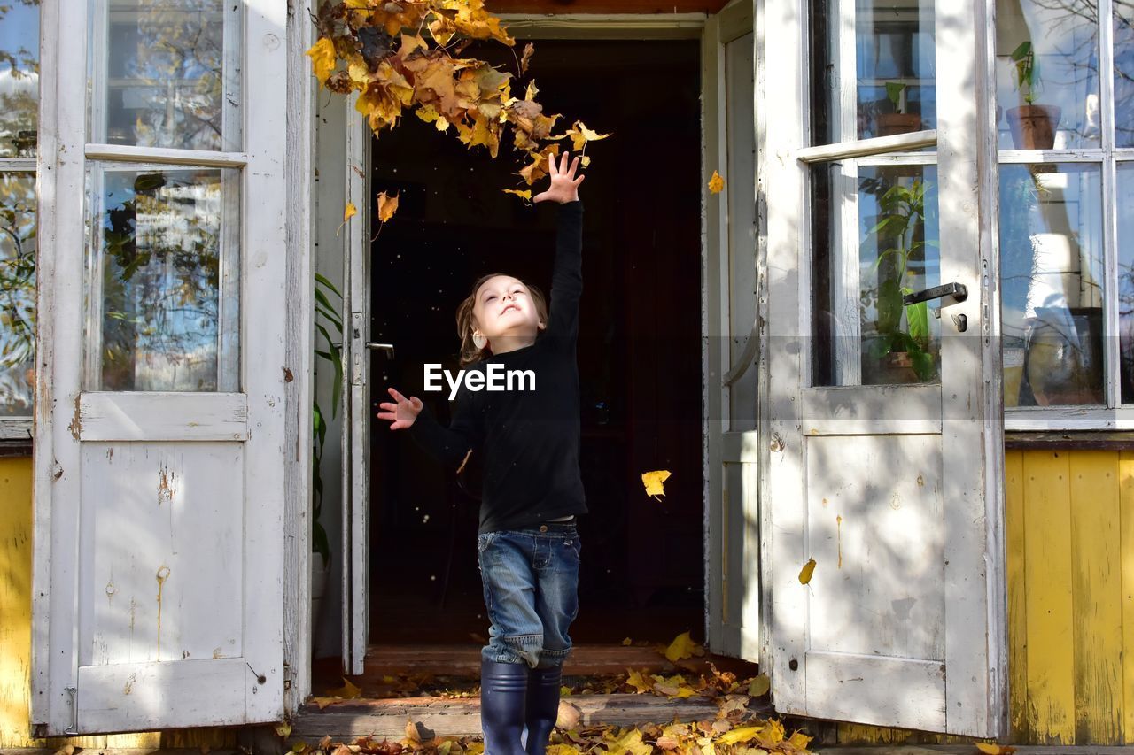 Boy throwing dry leaves against door