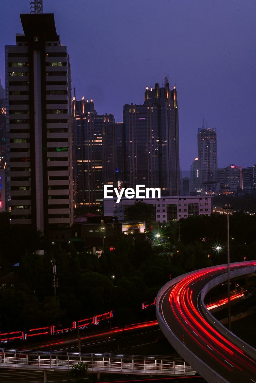 High angle view of light trails on road amidst buildings in city