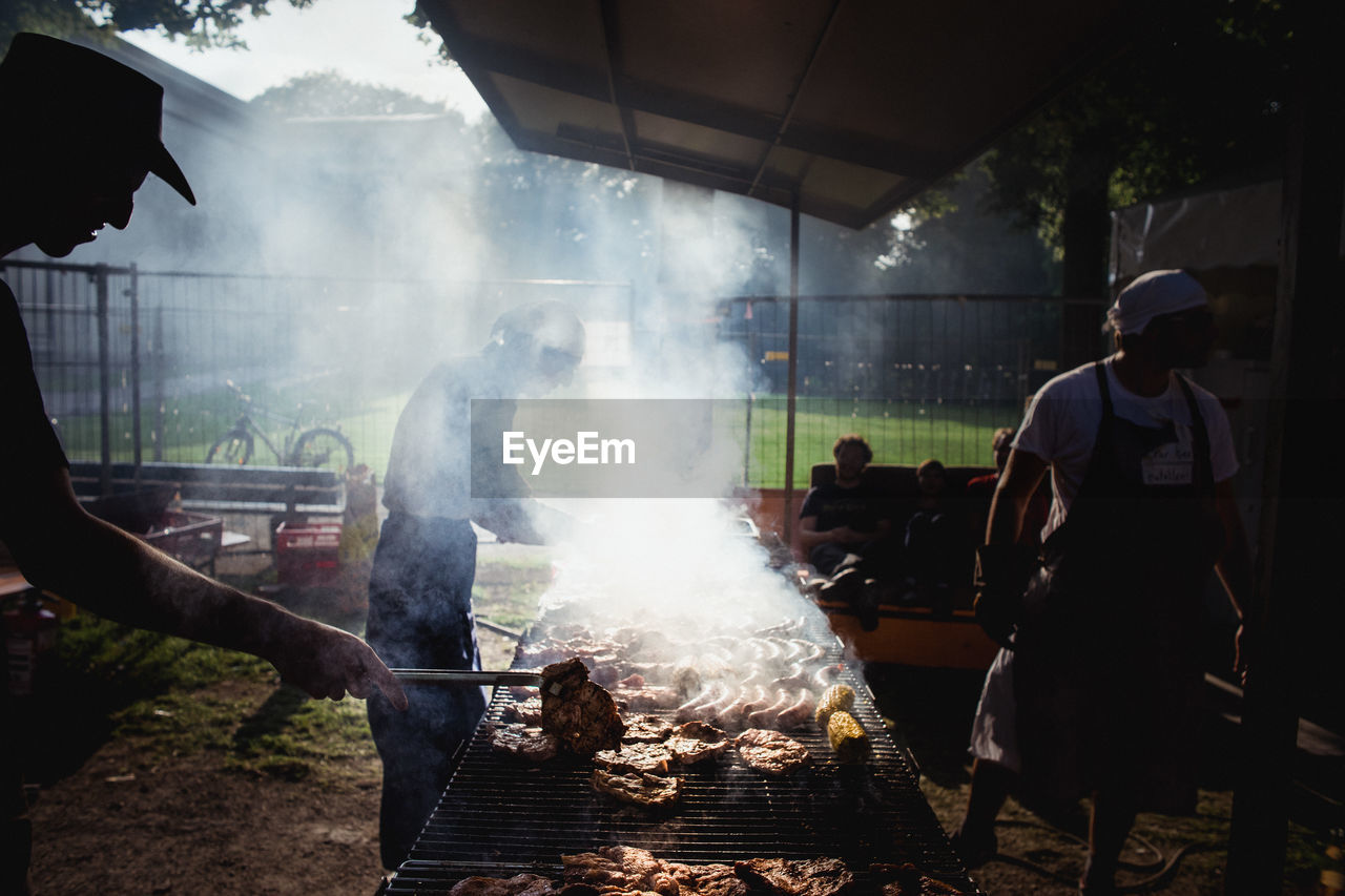 People grilling meat at barbeque grill