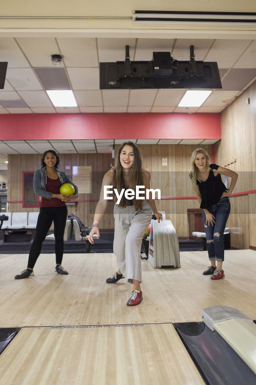 A young women bowling with friends.