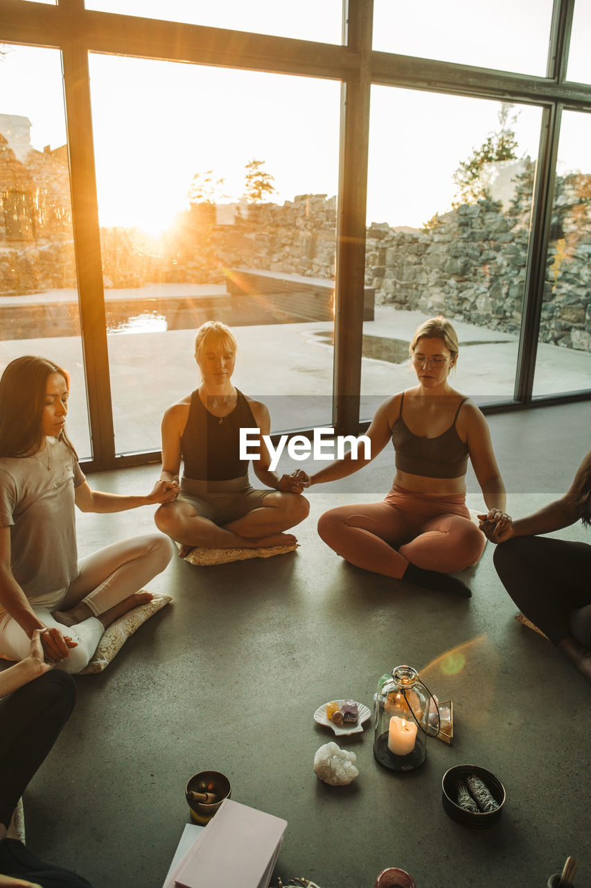 Young women holding hands while meditating at retreat center