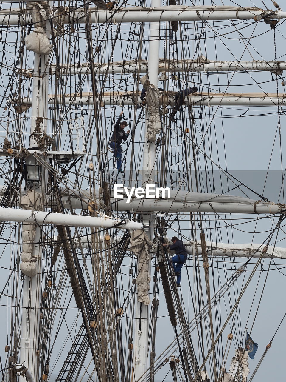 Low angle view of workers on ship against clear sky