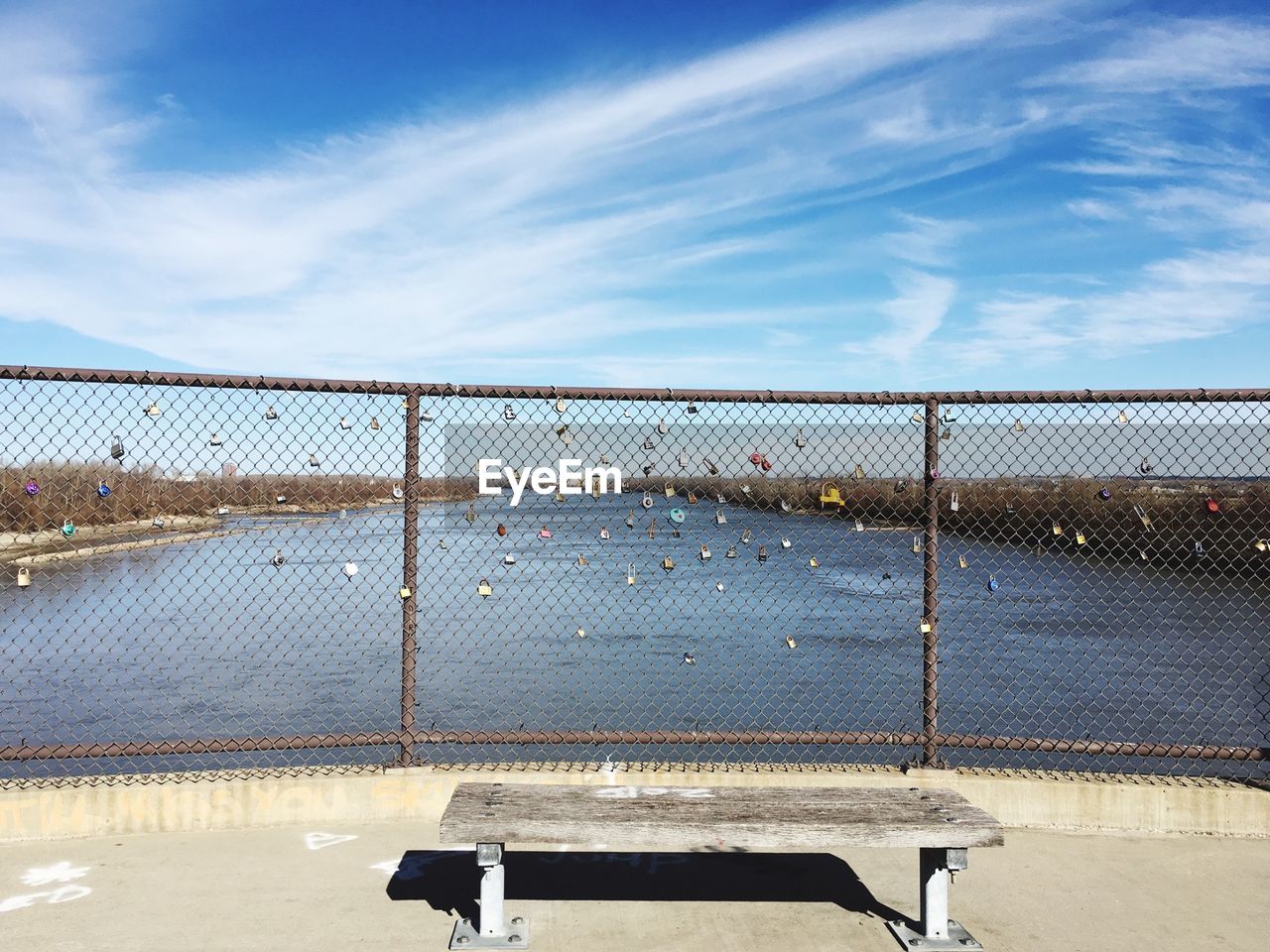 Padlocks attached to chainlink fence by lake