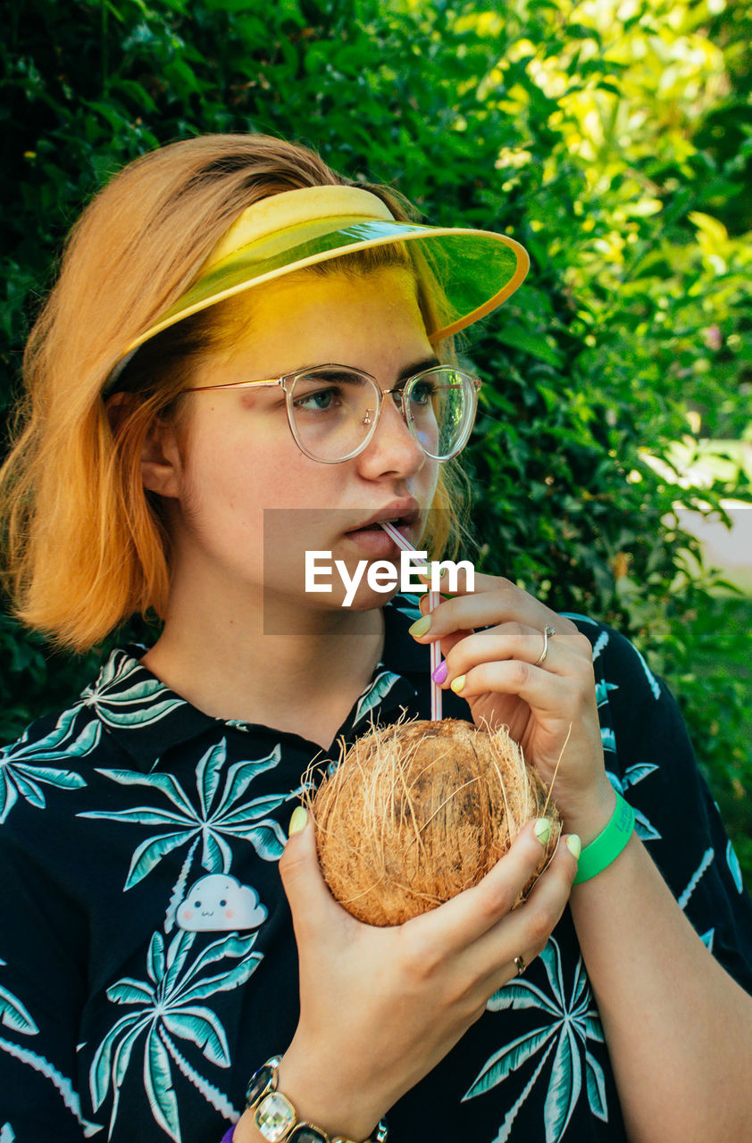 Young woman drinking coconut water with straw