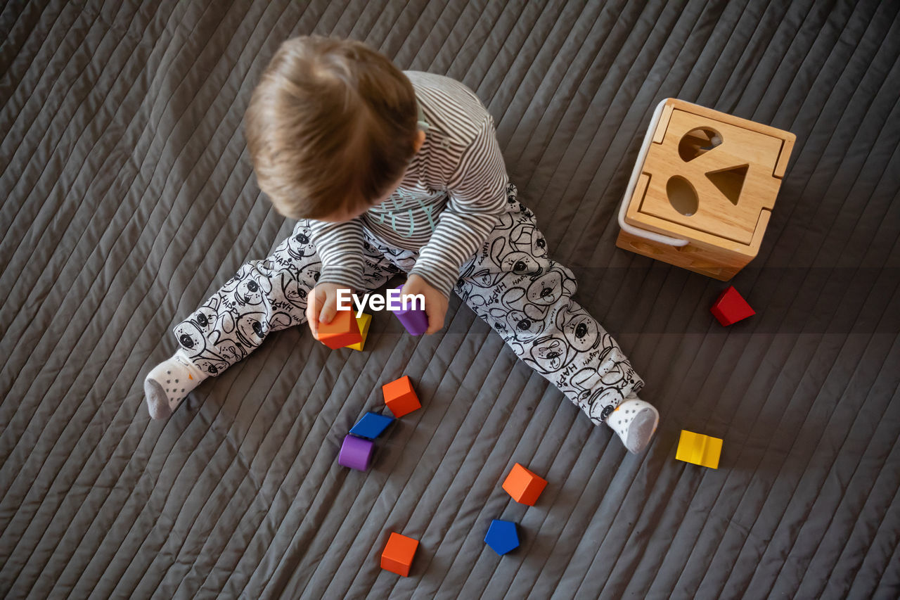 Directly above shot of boy with down syndrome playing on rug