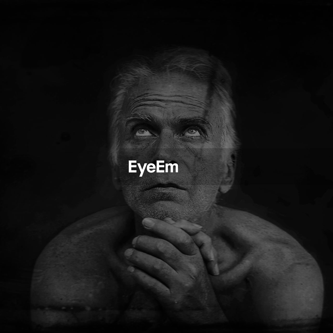 Worried mature man looking up against black background