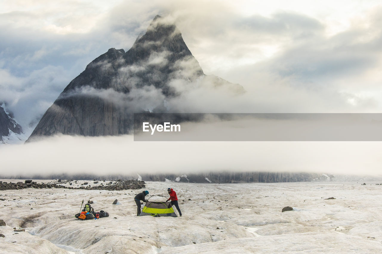 Two mountaineers below dramatic mountain in the arctic, baffin island