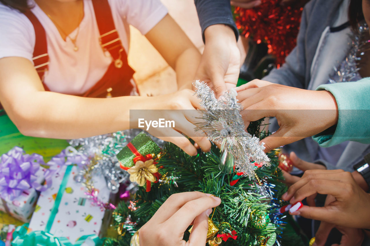 Cropped hands of family decorating christmas tree