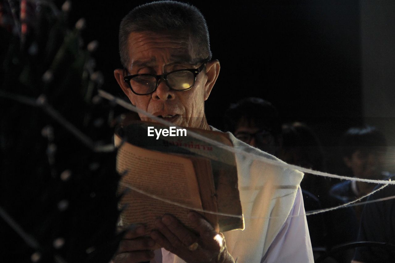 Senior man wearing eyeglasses reading book