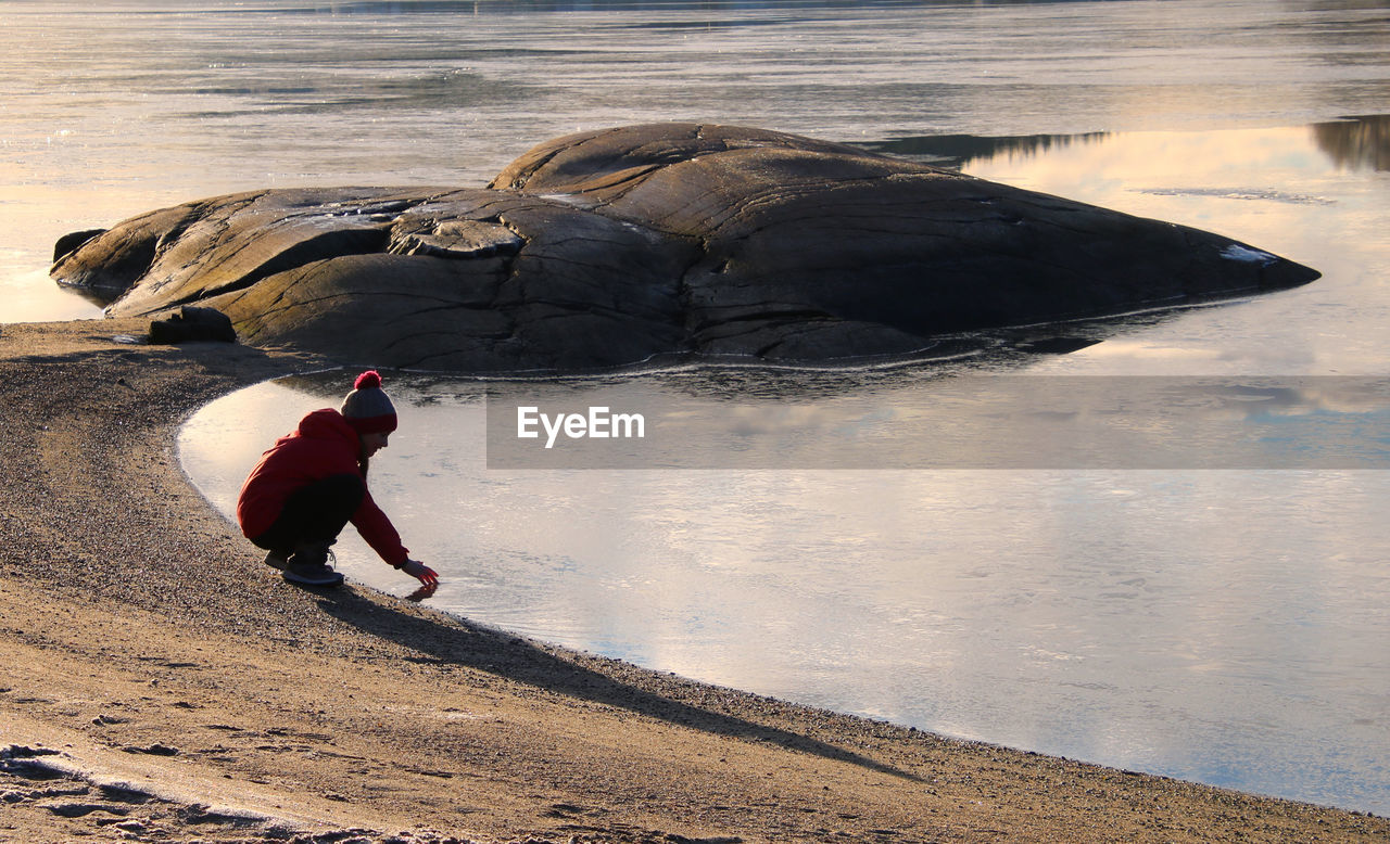 Side view of girl touching the frozen water