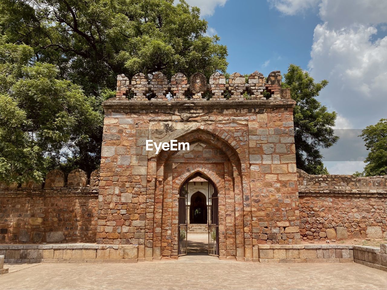 architecture, built structure, history, the past, tree, arch, plant, building exterior, travel destinations, entrance, nature, building, place of worship, ancient history, religion, brick, gate, ruins, ancient, sky, travel, cloud, wall, no people, historic site, outdoors, tourism, door, estate, day, belief, fortification, old