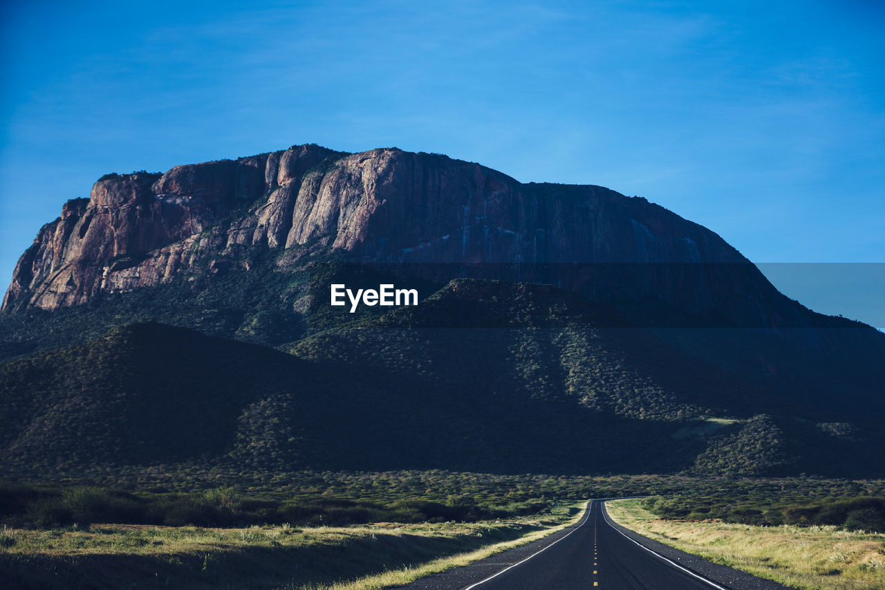 road, mountain, transportation, sky, landscape, scenics - nature, nature, environment, mountain range, the way forward, beauty in nature, horizon, land, no people, travel, travel destinations, blue, non-urban scene, cloud, outdoors, symbol, highway, tranquility, sign, rock, day, tranquil scene, mountain pass, road marking, vanishing point, diminishing perspective, marking, remote