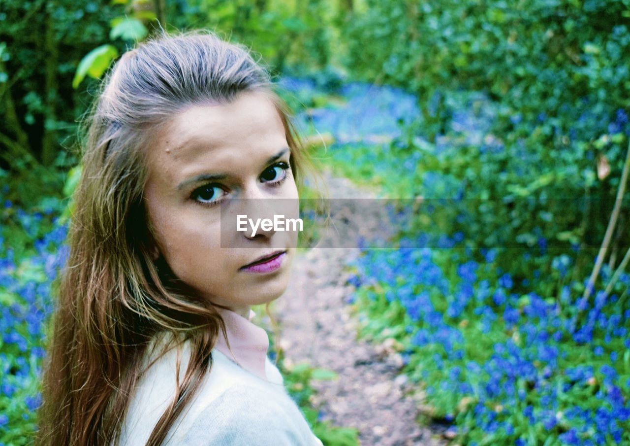 Portrait of young woman by plants on field