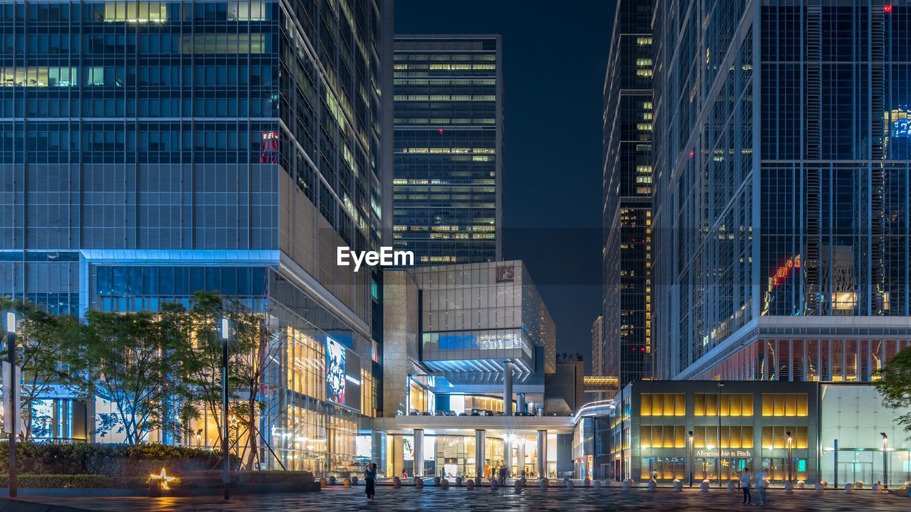 ILLUMINATED STREET AMIDST BUILDINGS AT NIGHT