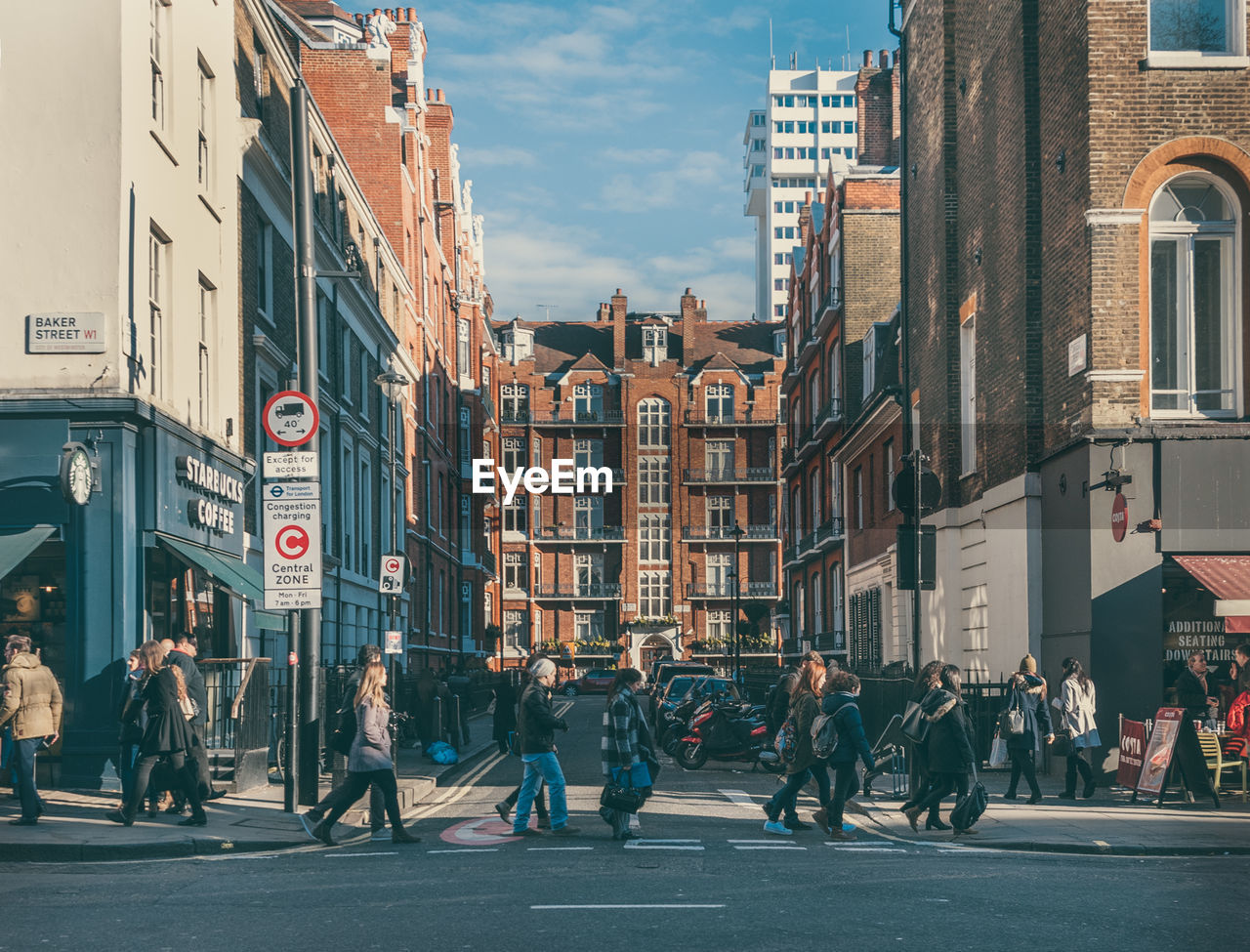 PEOPLE BY STREET IN CITY AGAINST SKY