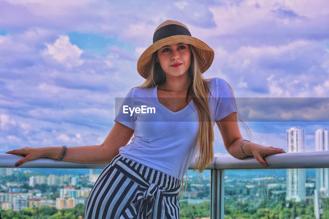 PORTRAIT OF BEAUTIFUL YOUNG WOMAN STANDING AGAINST SKY