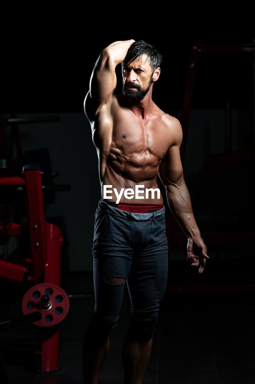 portrait of young man with arms crossed standing in gym