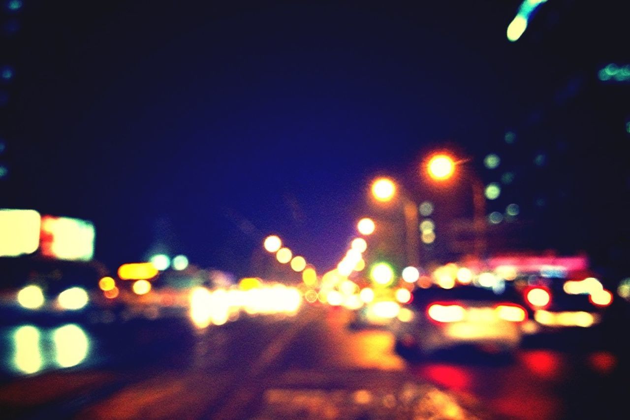 DEFOCUSED IMAGE OF ILLUMINATED CITY STREET AT NIGHT