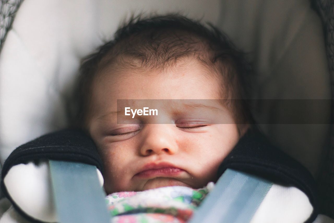 Close-up of cute baby girl sleeping on baby stroller 