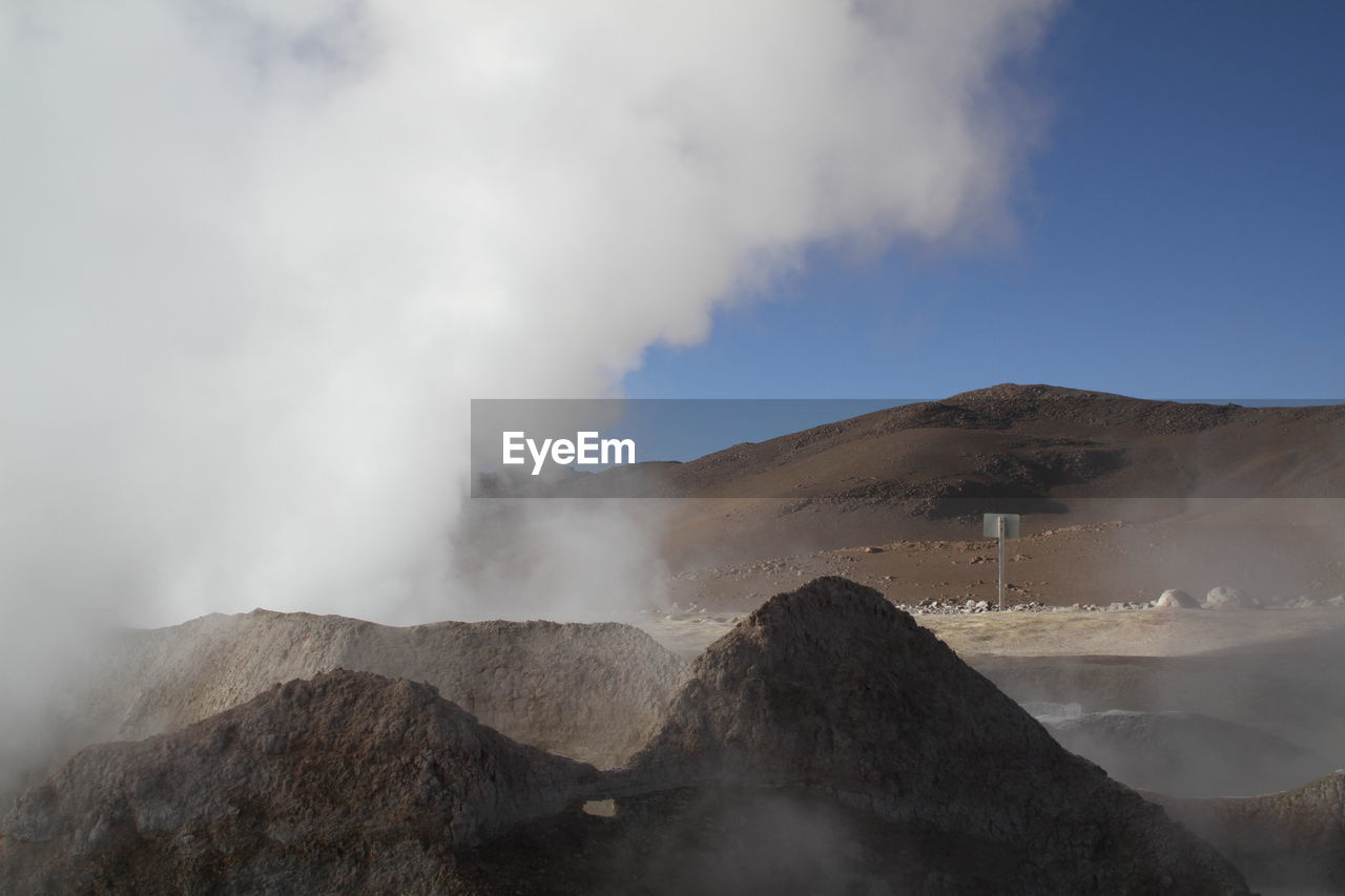 Steam emitting from geyser against sky