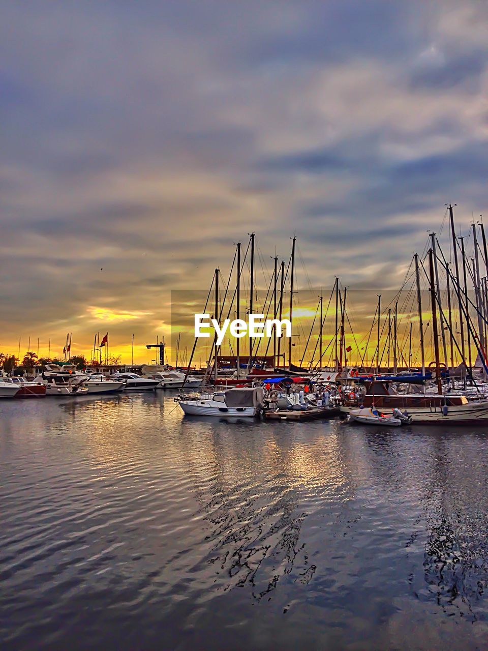 Sailboats moored in fenerbahce yat limani against sunset sky