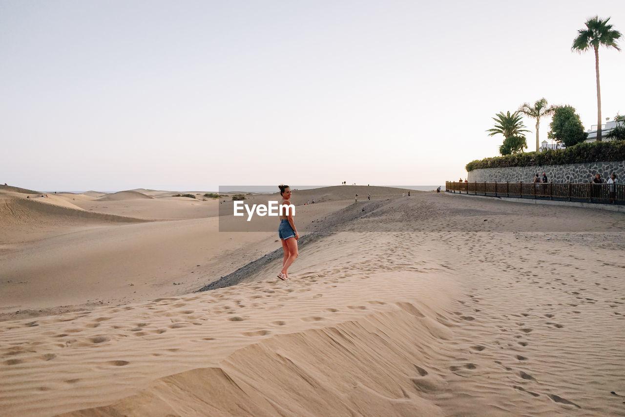 rear view of man walking at beach against clear sky