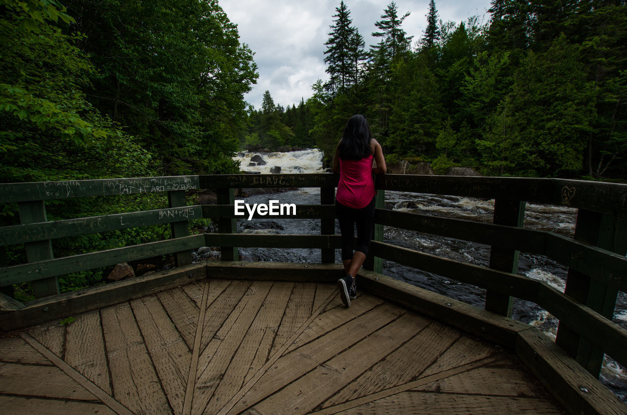 FULL LENGTH REAR VIEW OF WOMAN STANDING ON FOOTBRIDGE