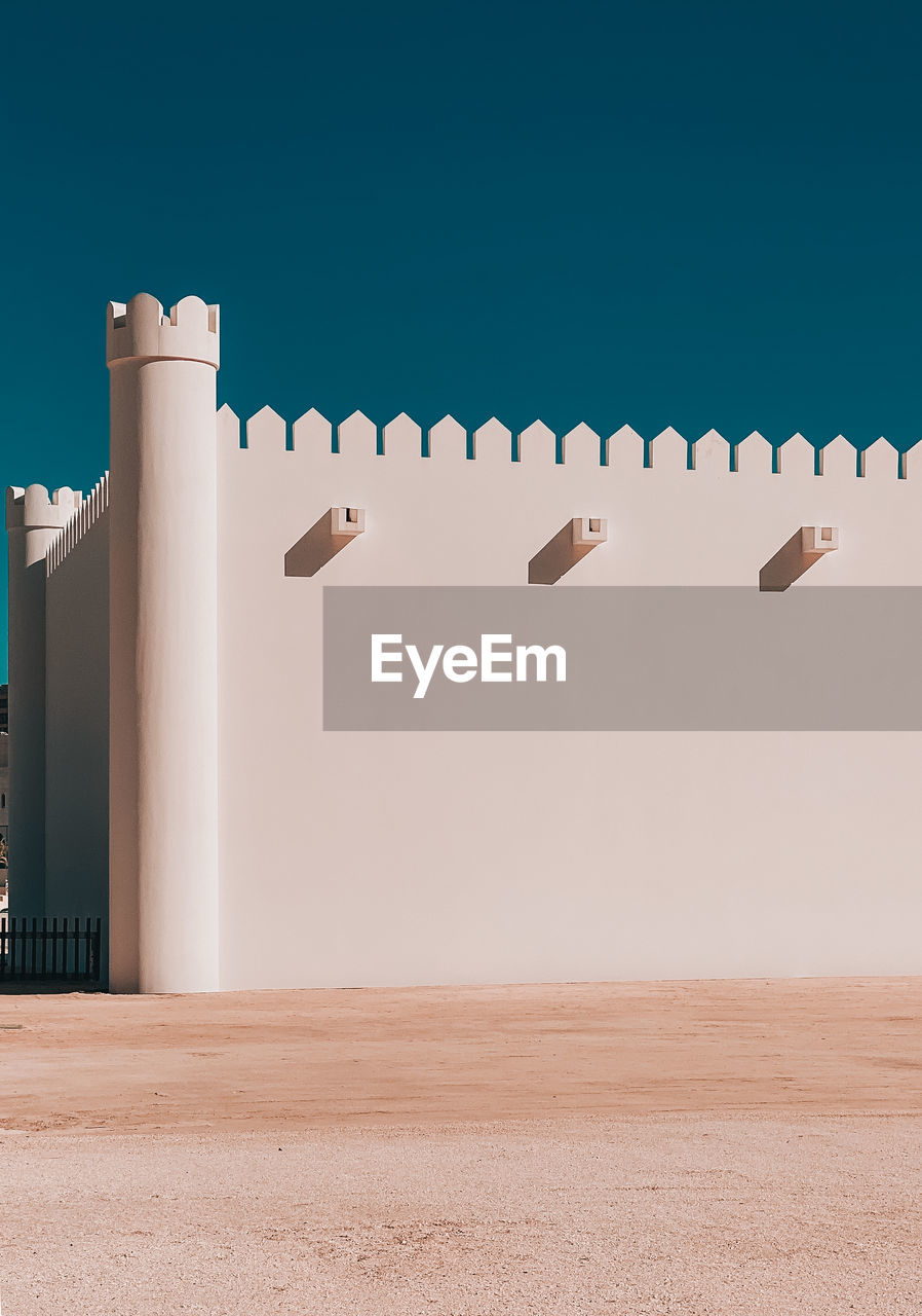 Flock of birds on wall against clear sky