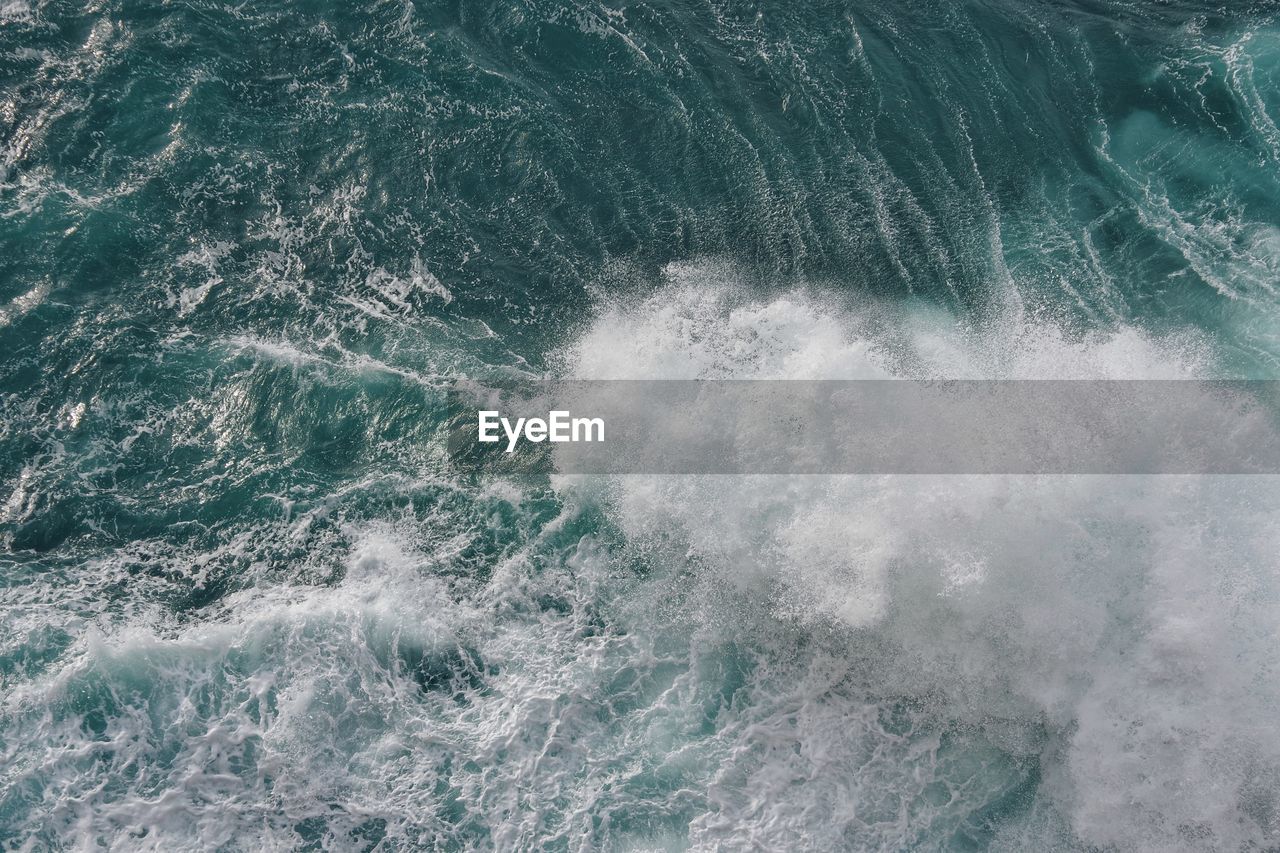 HIGH ANGLE VIEW OF SEA WAVES SPLASHING ON SHORE