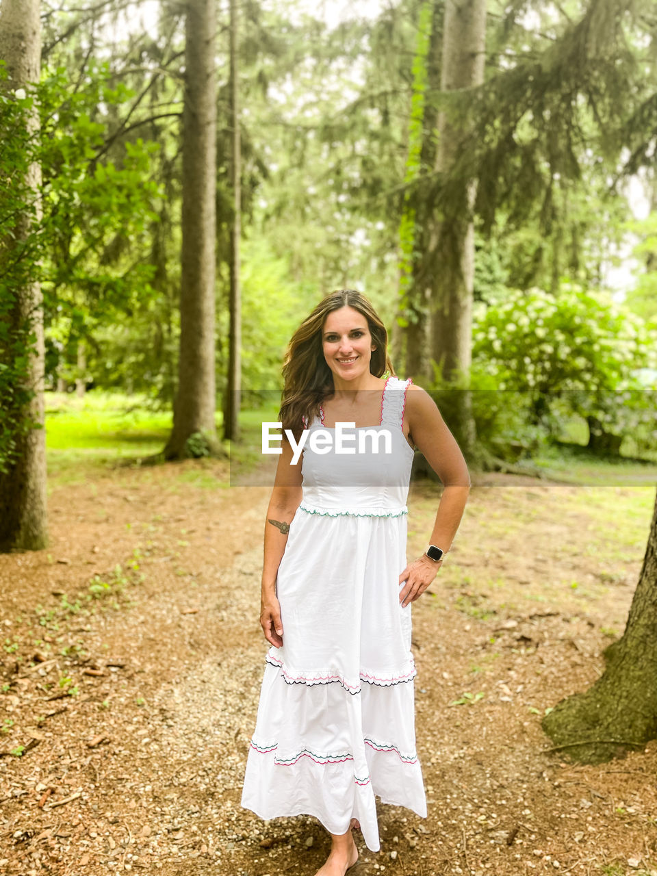 Young woman standing against trees