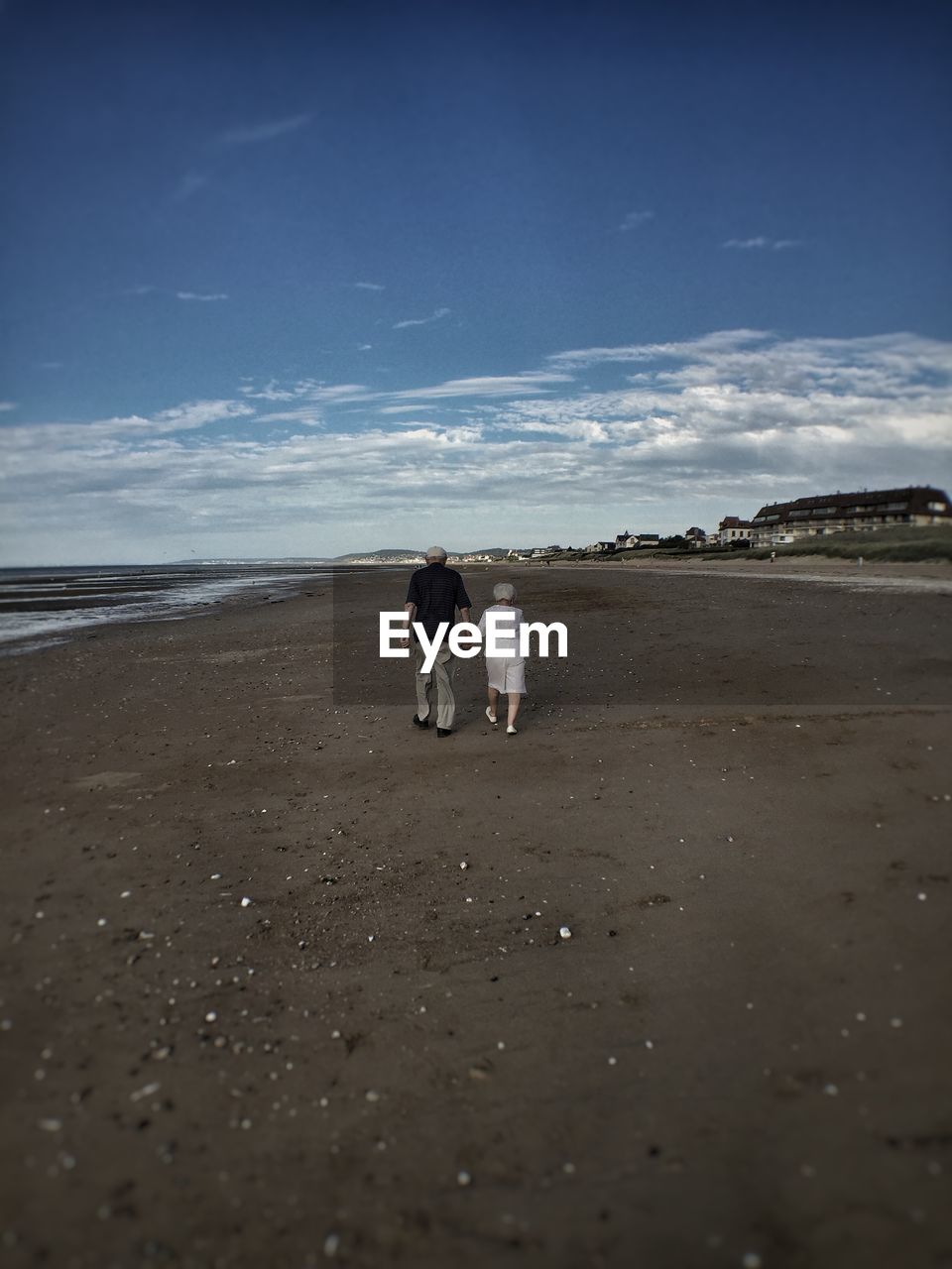 Full length of people walking on beach against sky