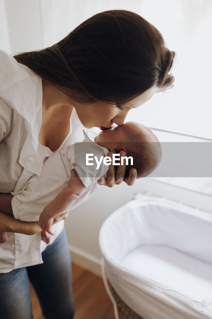 Young woman kissing newborn baby on forehead