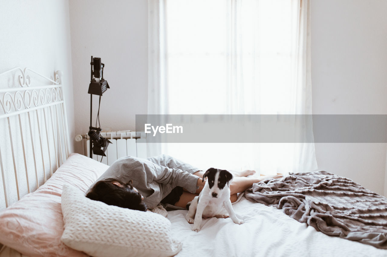 Young woman sleeping by dog on bed at home