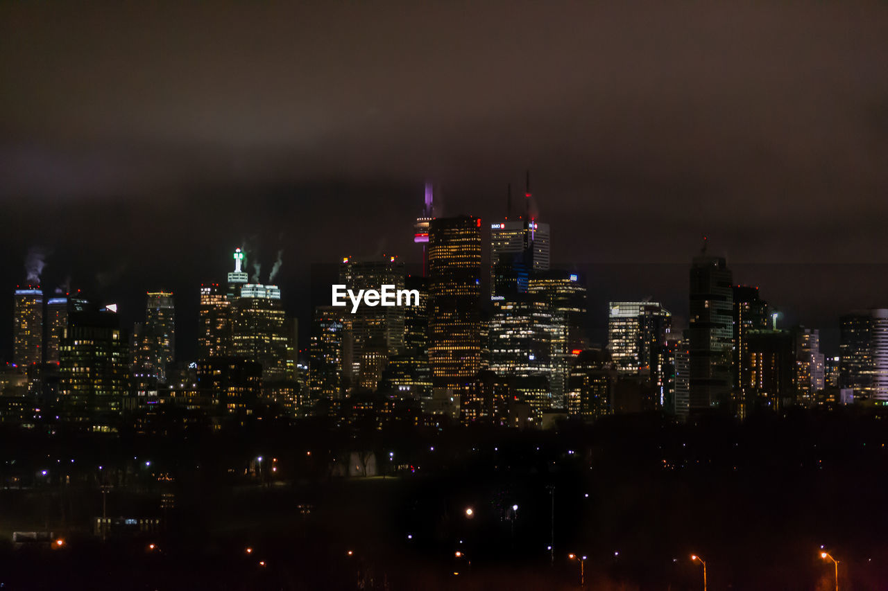 Illuminated buildings in city against sky at night