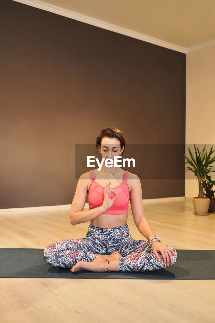 Young woman doing yoga on yoga mat in atmospheric yoga studio