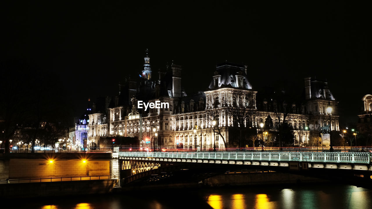 Illuminated bridge over river against sky at night