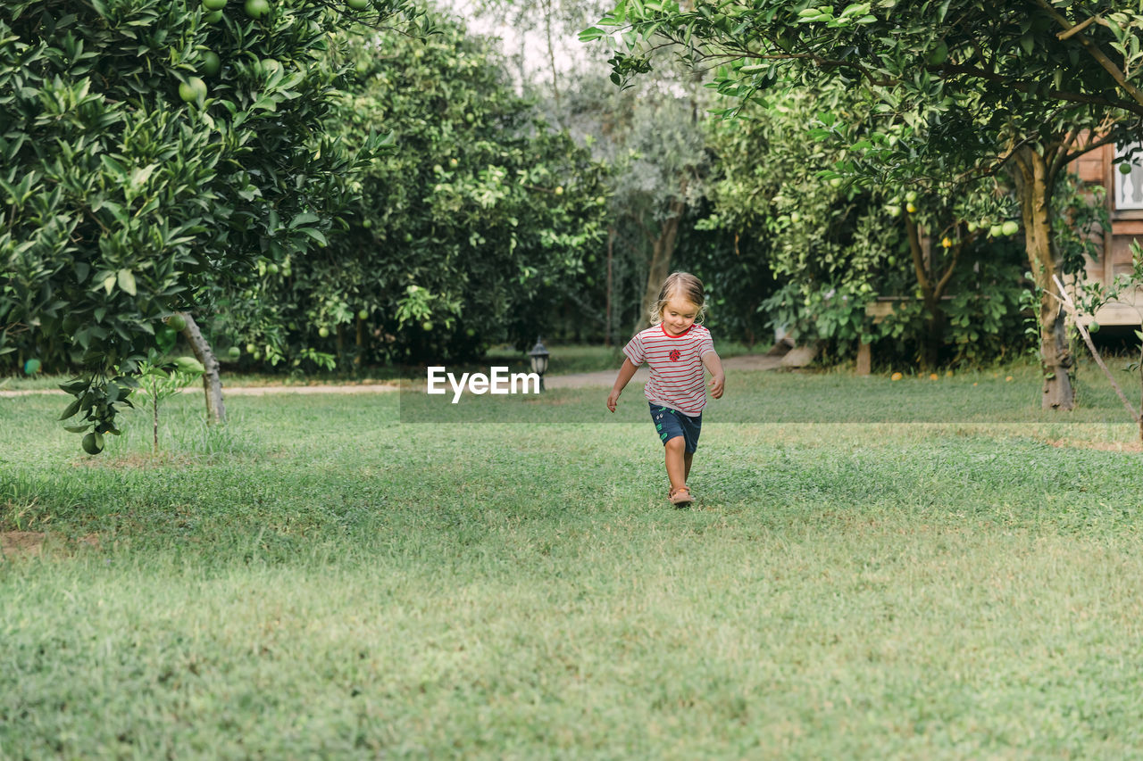 Full length of girl walking on grass against trees