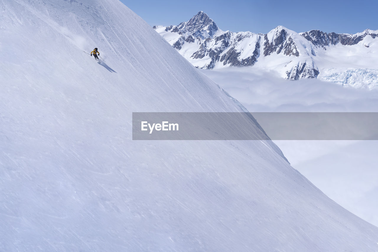 VIEW OF PEOPLE SKIING ON SNOWCAPPED MOUNTAINS