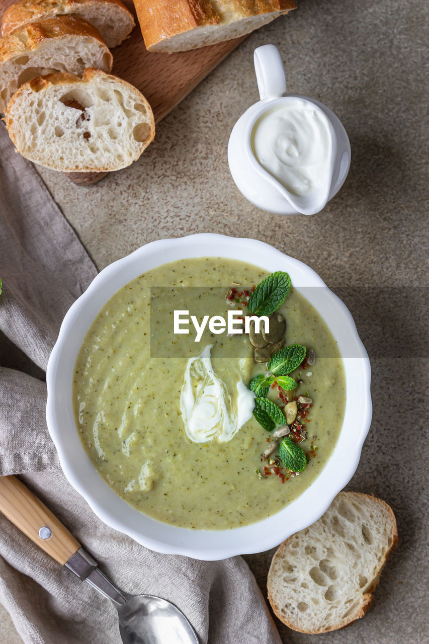Broccoli cream soup served with mint, cream, seeds and bread. healthy vegetarian food concept. 