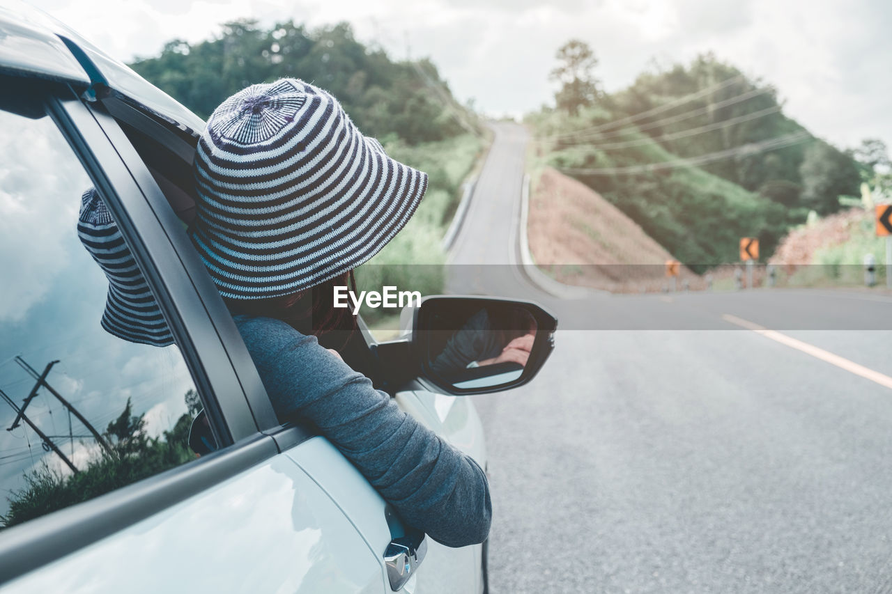 Rear view of woman traveling in car on road